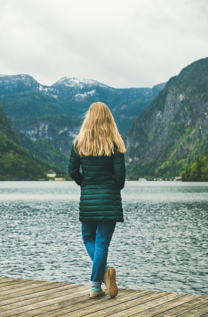 Female traveller standing at mountain lake coast in the Alps